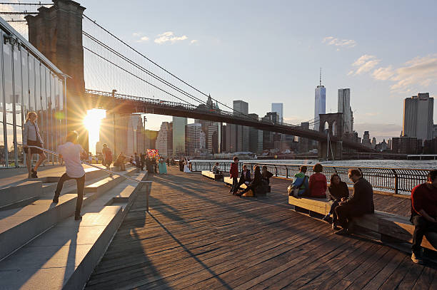 Sunset enjoyed at the waterfront of the Brooklyn Bridge Park New York, USA - October 04, 2014: Close to the Brooklyn Bridge, sunset at the Brooklyn bridge park. The One World Trade Center is seen in the back. großunternehmen stock pictures, royalty-free photos & images