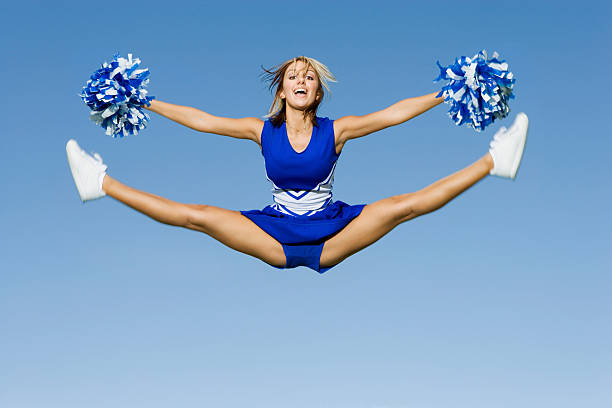 High school female cheerleader posing with her pom pom.