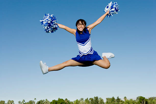 Cheerleader Performing Cheer in Mid-Air Jumping Cheerleader Performing Cheer in Mid-Air cheerleader photos stock pictures, royalty-free photos & images