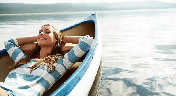 Loving the fresh air An attractive young woman relaxing and daydreaming in a canoe happy peaceful woman stock pictures, royalty-free photos & images