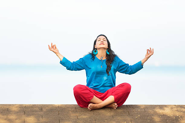 Yogi woman in padmasana pose with hands together on face in Srirangapatna temple, Karnataka, India