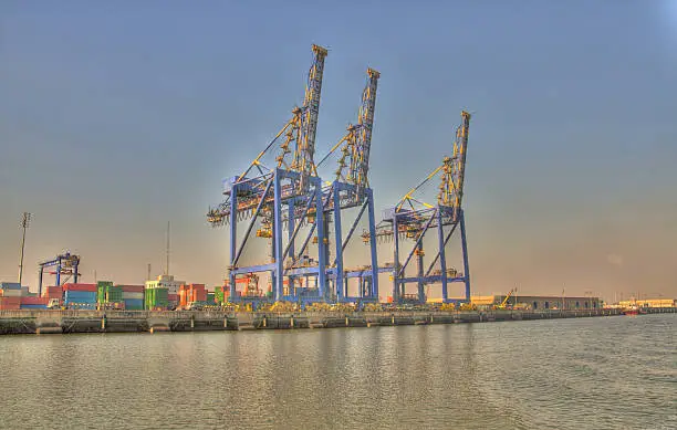 A view of three cargo lifting cranes