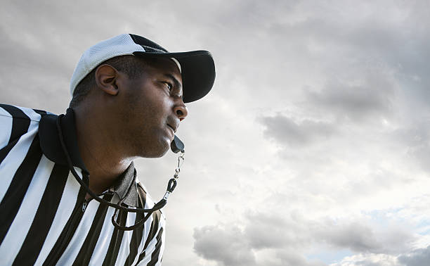 Referee Blowing Whistle During Football Game Referee Blowing Whistle During Football Game referee stock pictures, royalty-free photos & images