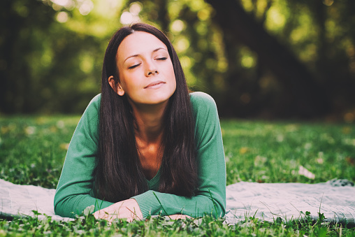 Beautiful young woman lying down in nature and thinking about something,intentionally toned image.