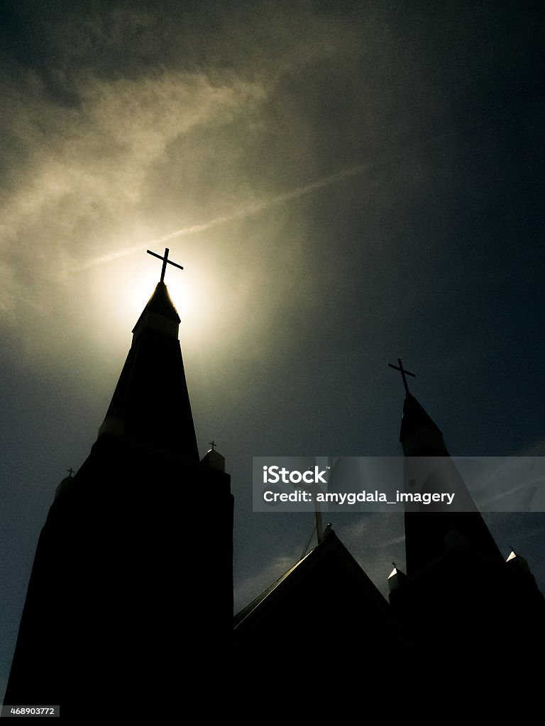 church and sunshine sky with crosses a church with crosses at the top of its steeples creates silhouette and shadow.  mobilestock vertical low angle composition created with iphone camera. 2015 Stock Photo