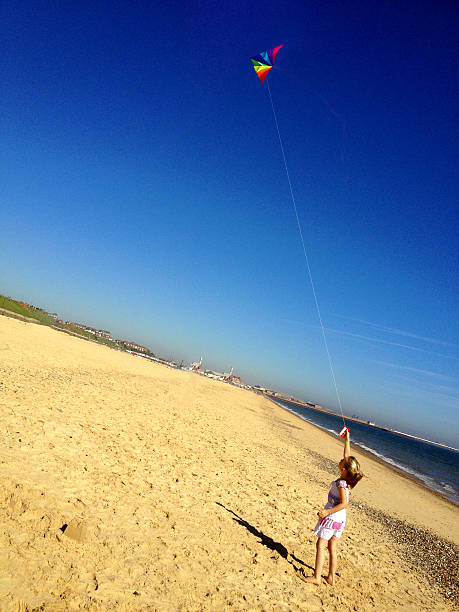 istock Little Girl Flying Kite on Beach 468903817