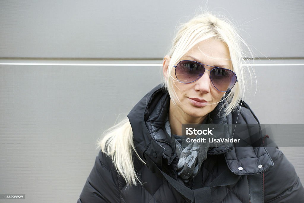 Portrait of mid adult woman Woman aged 35 - 45, blond hair, aviator sunglasses, wearing padded coat, looking serious 40-44 Years Stock Photo
