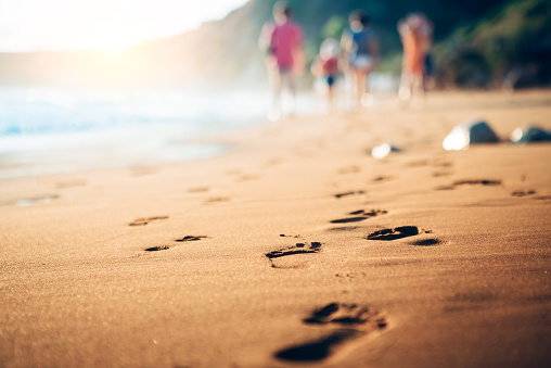 Family walking home from the sandy beach on Kefalonia Island (Avithos). Footsteps in the sand at sunset.