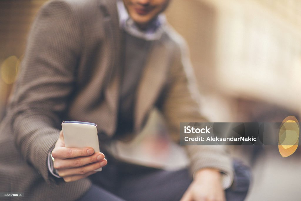 Smartphone in a man's extended hand Smiling man using a smartphone on the street / Focus is on the phone 25-29 Years Stock Photo
