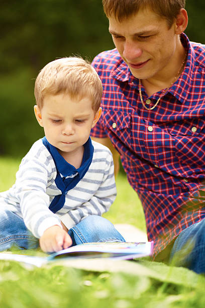 istock dad and little boy reading a book on the meadow 468910205