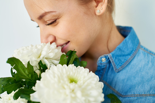 Young woman smelling white chrysanthemum flowers