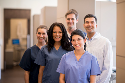 A group of doctors, nurses, and or dentists and professional assistants posing for a picture in a medical clinic.