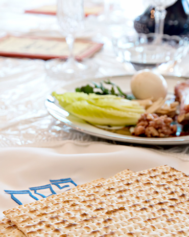 Our Passover Seder table with Matzoh, seder plate, wine, haggadah and salt water.