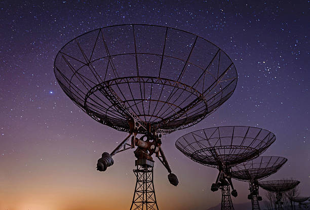 Low angled view of radio telescopes with Milky Way in sky stock photo