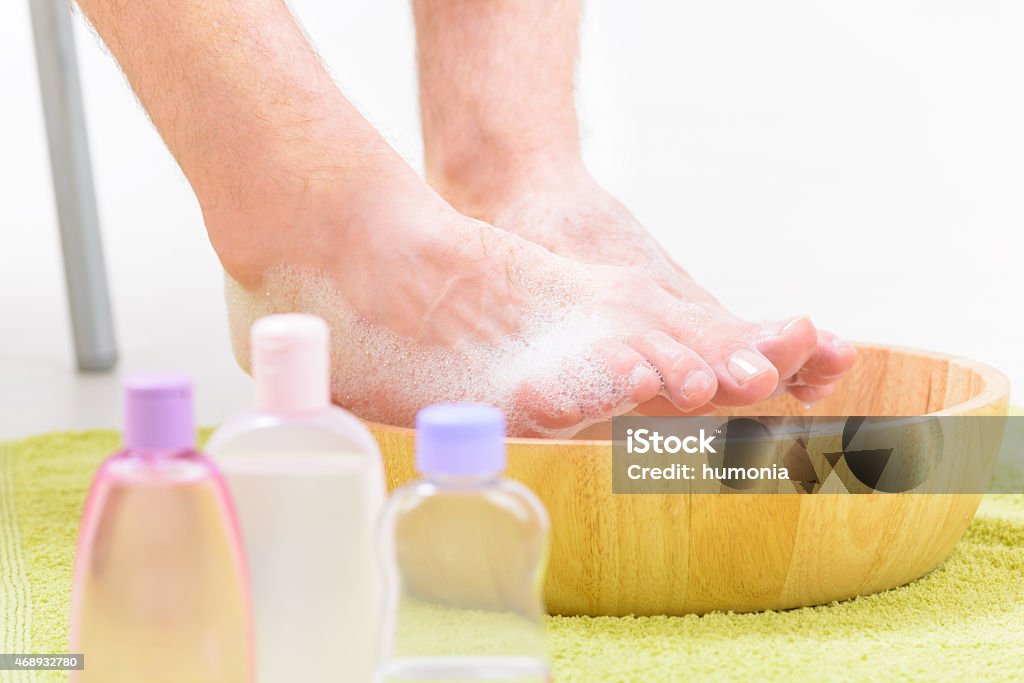 Male feets in a bowl Male feet in a bowl with water and soap, cosmetics in bottles, hygiene and spa concept 2015 Stock Photo