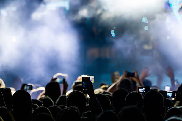 istock People taking photographs with touch smart phone during a music 468933264