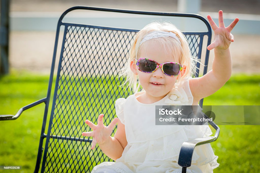 Cute Playful Baby Girl Wearing Sunglasses Outside at Park Cute Playful Baby Girl Wearing Sunglasses Outside at the Park. 2015 Stock Photo