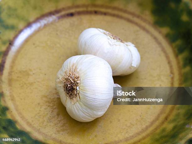 Pair Of Garlic Bulbs In Antique Yellowgreen Ceramic Bowl Stock Photo - Download Image Now