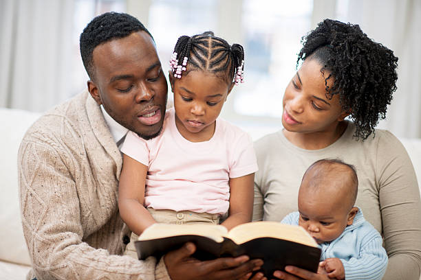 familia leyendo el libro juntos - reading religious text black bible fotografías e imágenes de stock