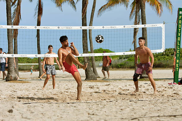 junge männer kick-fußball auf dem beach volleyball-platz - swimming trunks fotos stock-fotos und bilder