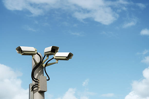 Security cctv surveillance camera Security cctv surveillance camera in front of blue sky with copy space big brother orwellian concept photos stock pictures, royalty-free photos & images