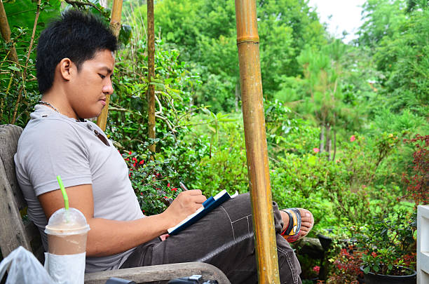 istock Thai man writing memory on book in the garden 468955850