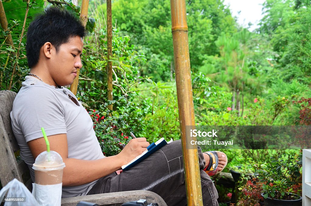 Thai man writing memory on book in the garden Thai man writing memory on book in the garden at Pang Ung (Pang Oong) or Pangtong2 of Mae Hong Son,Thailand 2015 Stock Photo