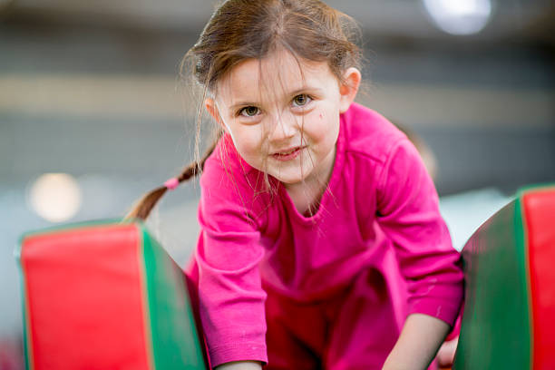 An elementary age girl playing on an obstacle course at recess or daycare.