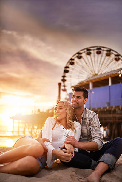 istock romantic couple relaxing on beach at santa monica 468957426