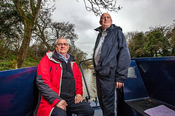 istock Two senior men steering canal boat 468957474