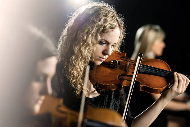 Woman playing violin. Three women playing musical instruments. Focus is on the middle, on young woman playing violin. string ensemble stock pictures, royalty-free photos & images