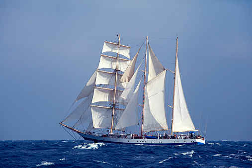 Group of attractive young women spending time on sailing vacation. They are enjoying, having fun, sunbathing, taking photos, jumping into the sea from the sailboat They look happy and relaxed.