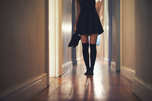 On her way out Cropped image of a young woman walking down the hallway in her house woman putting on socks stock pictures, royalty-free photos & images