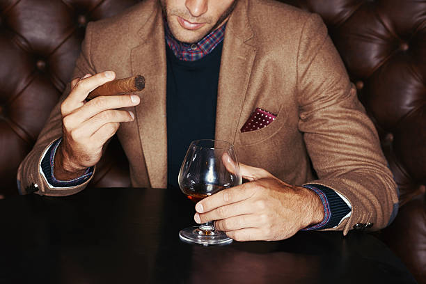 Showing off his wealth A stylish man drinking whiskey and smoking a cigar man cigar stock pictures, royalty-free photos & images