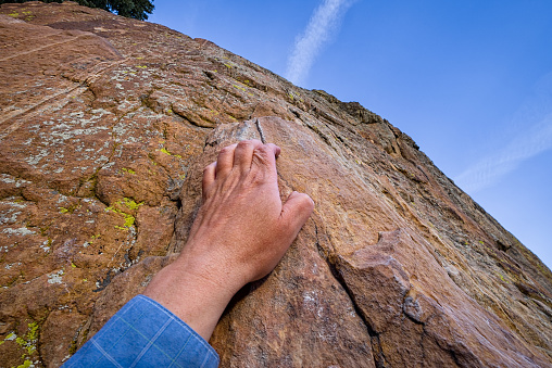 Hand Holding On To Steep Rock Cliff - Precariously holding on with one hand.