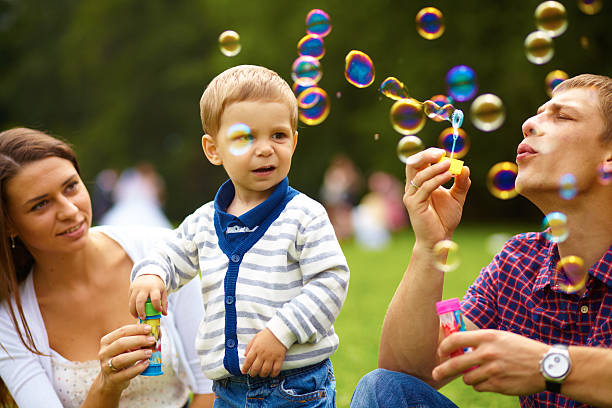 istock Attractive Young Parents Having Fun Blowing Bubbles with their 468966357