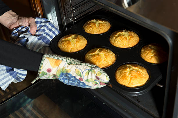 Woman baking in a domestic kitchen, Slovenia, Europe. Focus on left hand and muffins..