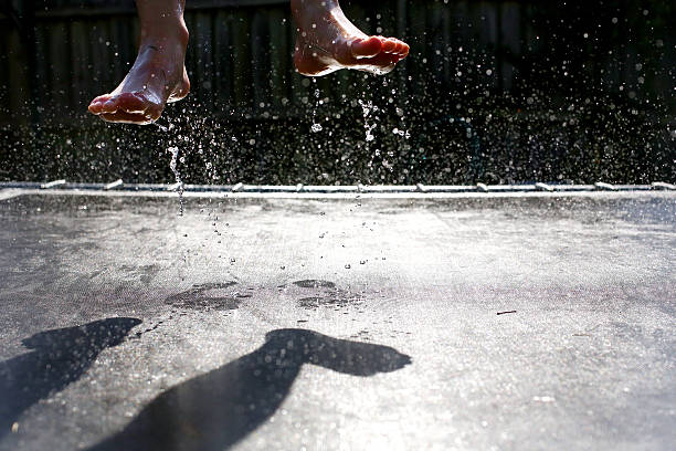 A child's wet feet are seen as she jumps on a trampoline