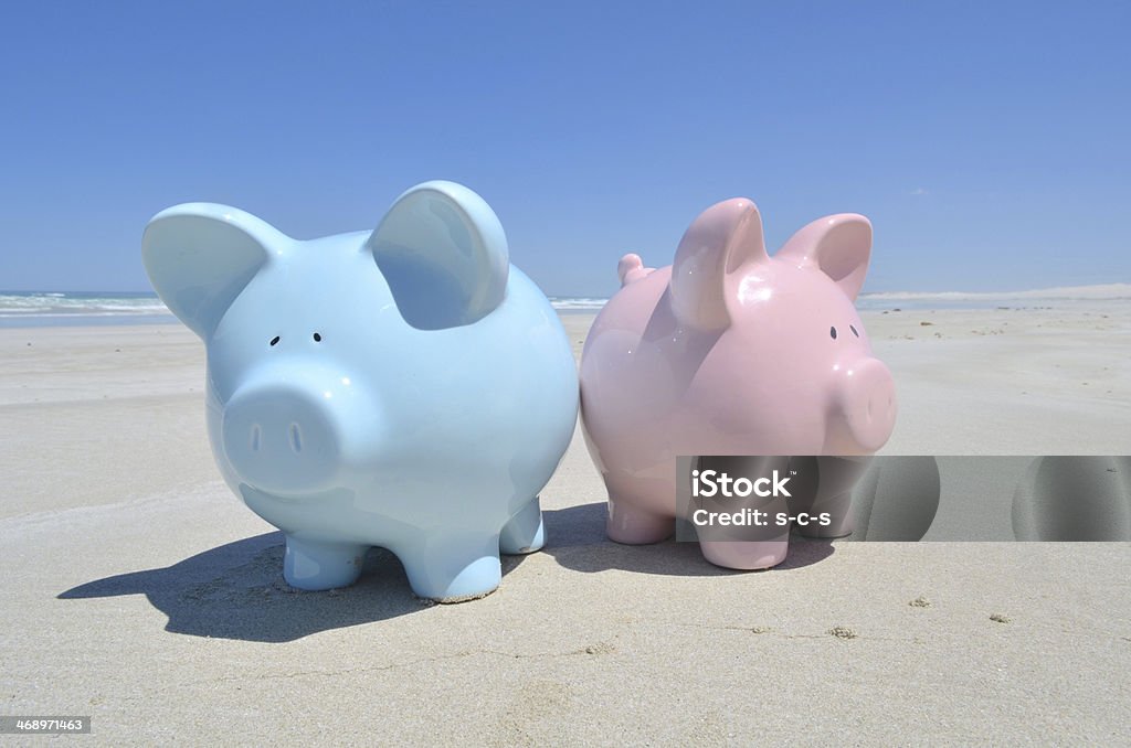 Saving for a Honeymoon A pink and blue piggybank on the beach Finance Stock Photo