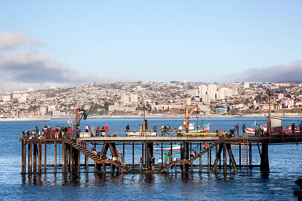 Valparaiso, Chile-April 3,2015: Some people fishing off the side of the pier in Valparaiso, face the downtown cityscape across Valparaiso Bay.