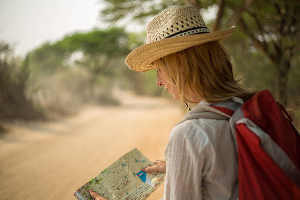 istock Lost traveler on desert road reading map 468977262