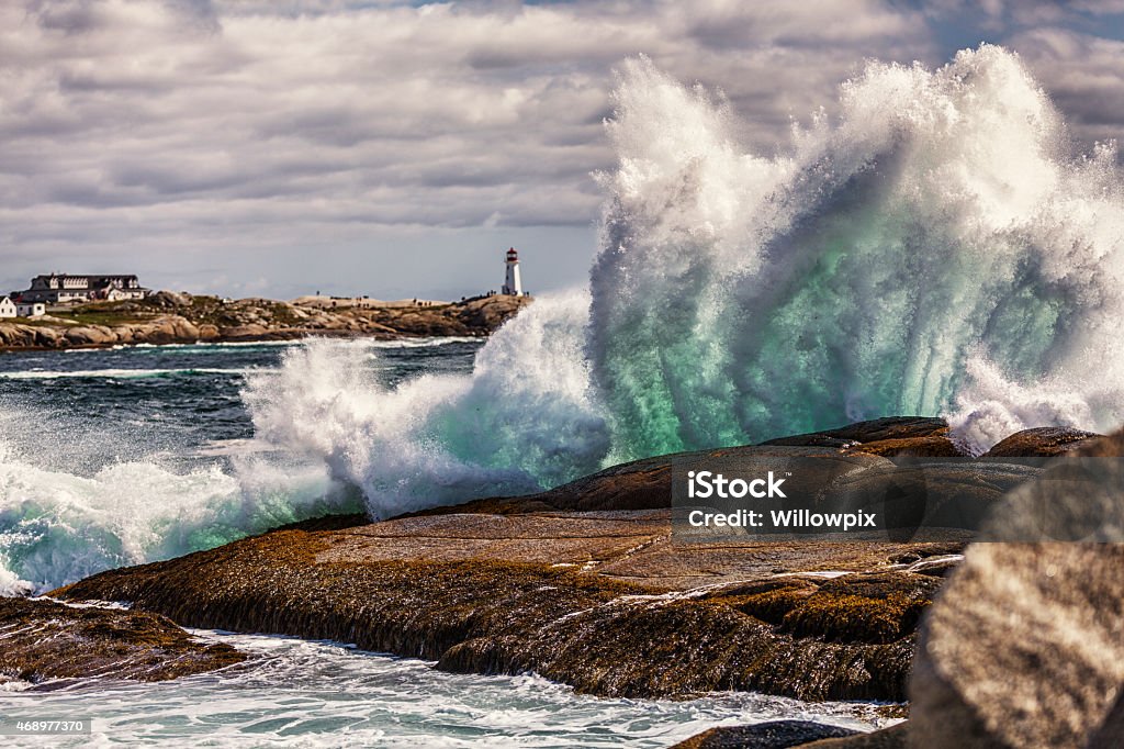 Windswept Heavy Surf at Peggys Cove Nova Scotia Canada An offshore storm sends high, heavy, windswept ocean surf/breakers crashing up and over the coastal shoreline rocks at Peggy's Cove, Nova Scotia, Canada. Peggy's Cove lighthouse is in the background. Canon 5D Mark III. Rock - Object Stock Photo