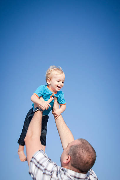 istock Young father and son playing laughing against a blue sky 468978922
