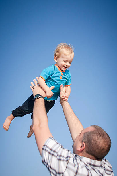 istock Young father and son playing laughing against a blue sky 468978934