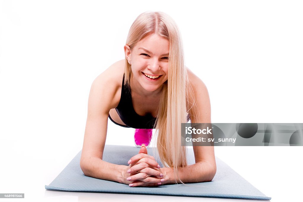 Fitness woman looking at camera isolated on white background. Photography of Fitness woman looking at camera isolated on white background. Smiling happy female fitness model doing plank pose. 2015 Stock Photo