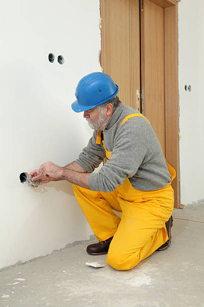 Electrician at construction site install electrical plug Electrician installing electrical plug at wall and using voltage testing screwdriver cable tester stock pictures, royalty-free photos & images