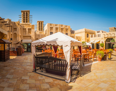 Al fresco restaurant in traditional style square overlooked by wind towers and clear blue desert skies, Dubai, United Arab Emirates. ProPhoto RGB profile for maximum color fidelity and gamut.