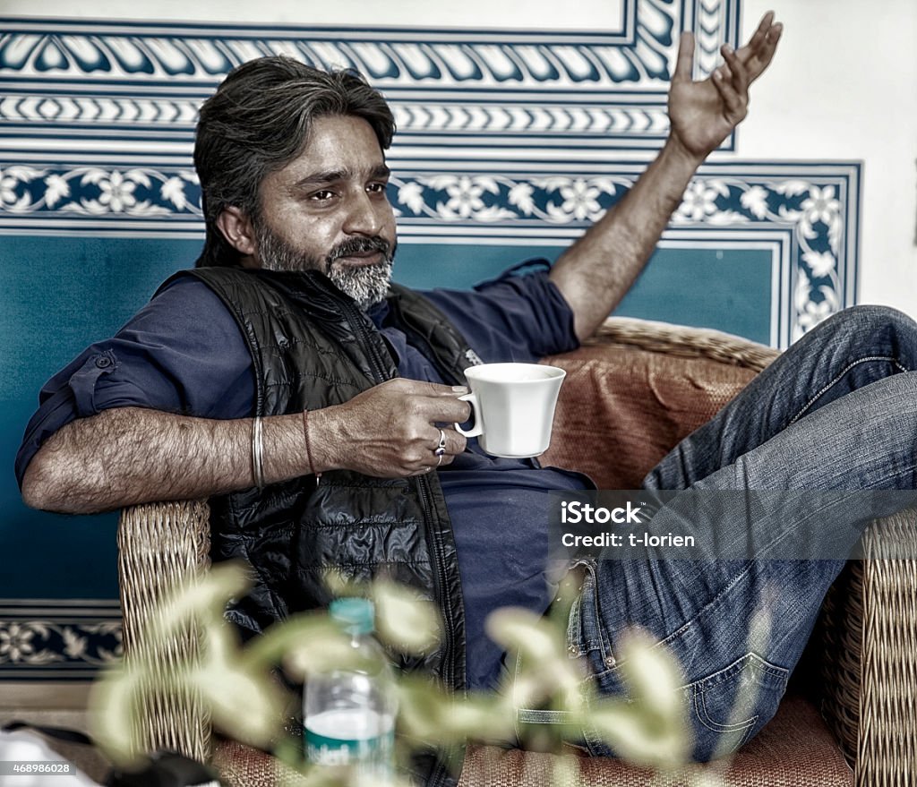 Indian man discussing. Indian man sitting relaxed in picturesque interior, gesturing while discussing & planning. Jodhpur - India 2015 Stock Photo