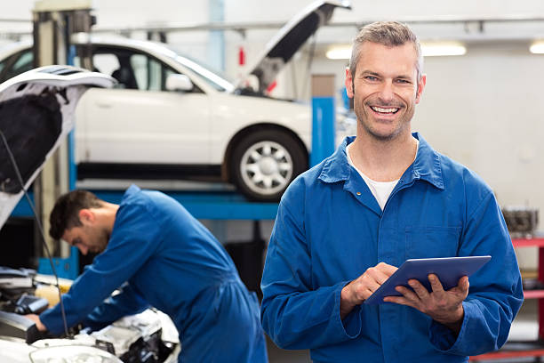 uśmiechająca się mechanik za pomocą tabletu - auto repair shop adult auto mechanic blue zdjęcia i obrazy z banku zdjęć