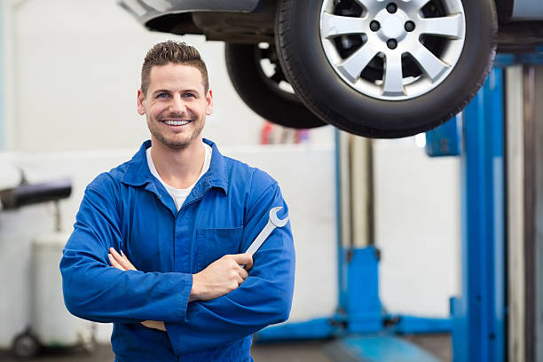 Mechanic smiling at the camera holding tool Mechanic smiling at the camera holding tool at the repair garage auto mechanic photos stock pictures, royalty-free photos & images